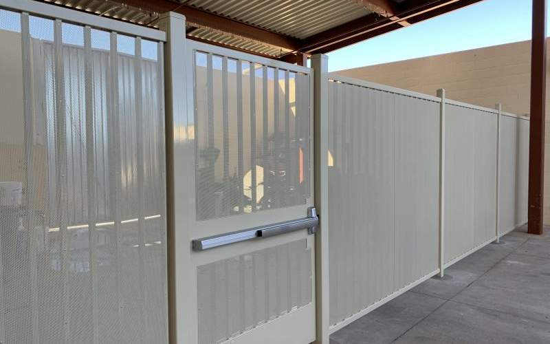 A white commercial wrought iron fence with a gate