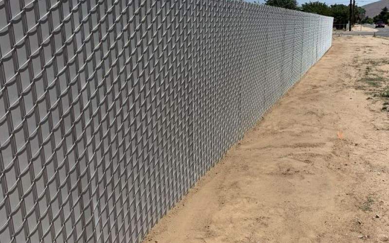 Grey privacy chain link fence surrounding a yard