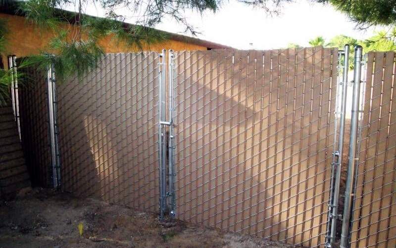 A brown privacy chain link with double swing gates